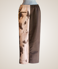 A pair of wide-leg cropped pants displayed on a mannequin torso against a plain light background. The pants feature a split design: one side has a beige and brown abstract print, and the other side is solid dark brown.