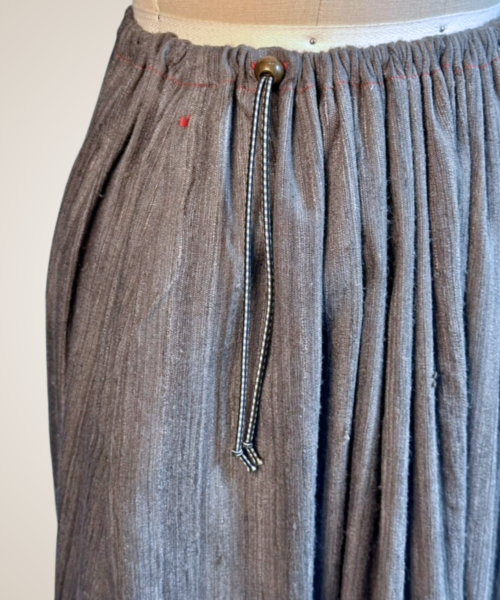 A close-up of a gray patterned button-up shirt jacket displayed on a dress form mannequin. The fabric features a textured, woven geometric tribal pattern in shades of gray and black, with three gold-tone buttons down the front.