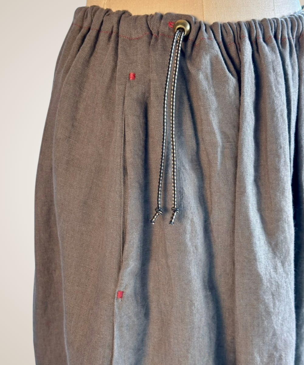 A close-up of a gray patterned button-up shirt jacket displayed on a dress form mannequin. The fabric features a textured, woven geometric tribal pattern in shades of gray and black, with three gold-tone buttons down the front.