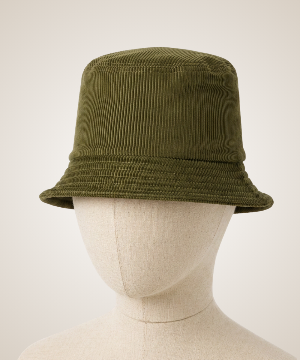 A textured olive knit cap with a curved brim, displayed on a beige fabric mannequin head against a light beige background.